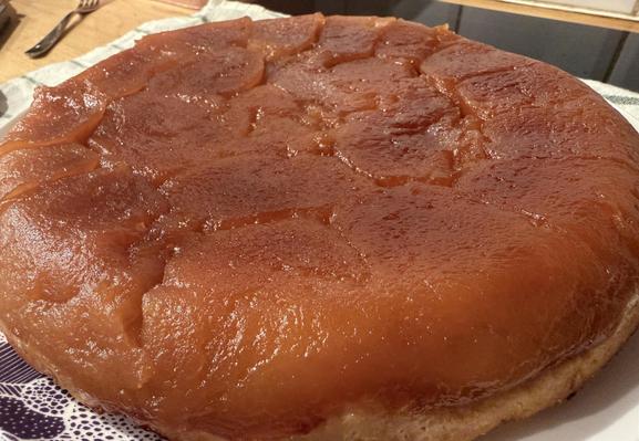 Gros plan sur la tarte tatin, on voit qu’elle est bien épaisse, les pommes luisent à la lumière, elle a l’air très généreuse