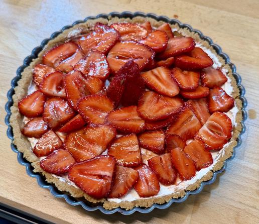 Une belle tarte dans un moule en métal. Toutes les fraises sont sur le dos, coupées en deux et très brillantes. 